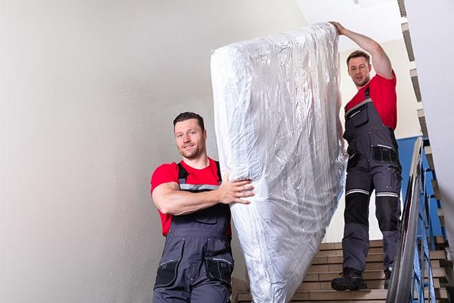 team of workers lifting a box spring out of a house in Goodyear, AZ